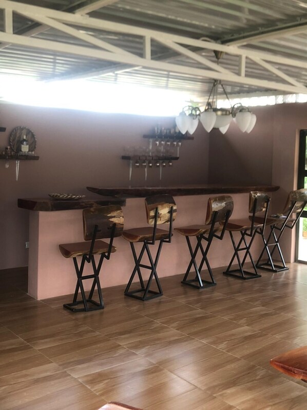 A bar area with a high ceiling, exposed beams, and a row of bar stools. - 1 bed Apartment in Mount Pleasant Heights - 2014 (Harare)