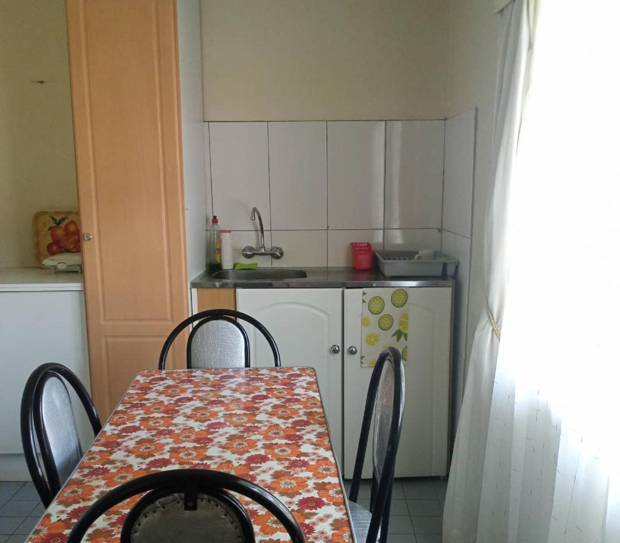Una piccola cucina con tavolo e sedie, lavello e pensili.
