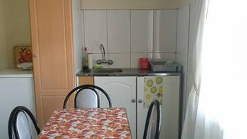 Una piccola cucina con tavolo e sedie, lavello e pensili.
