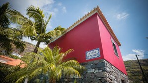 Un bâtiment rouge avec une base en pierre et une enseigne sur laquelle on peut lire : « A CASA DO PALHEIRO ».