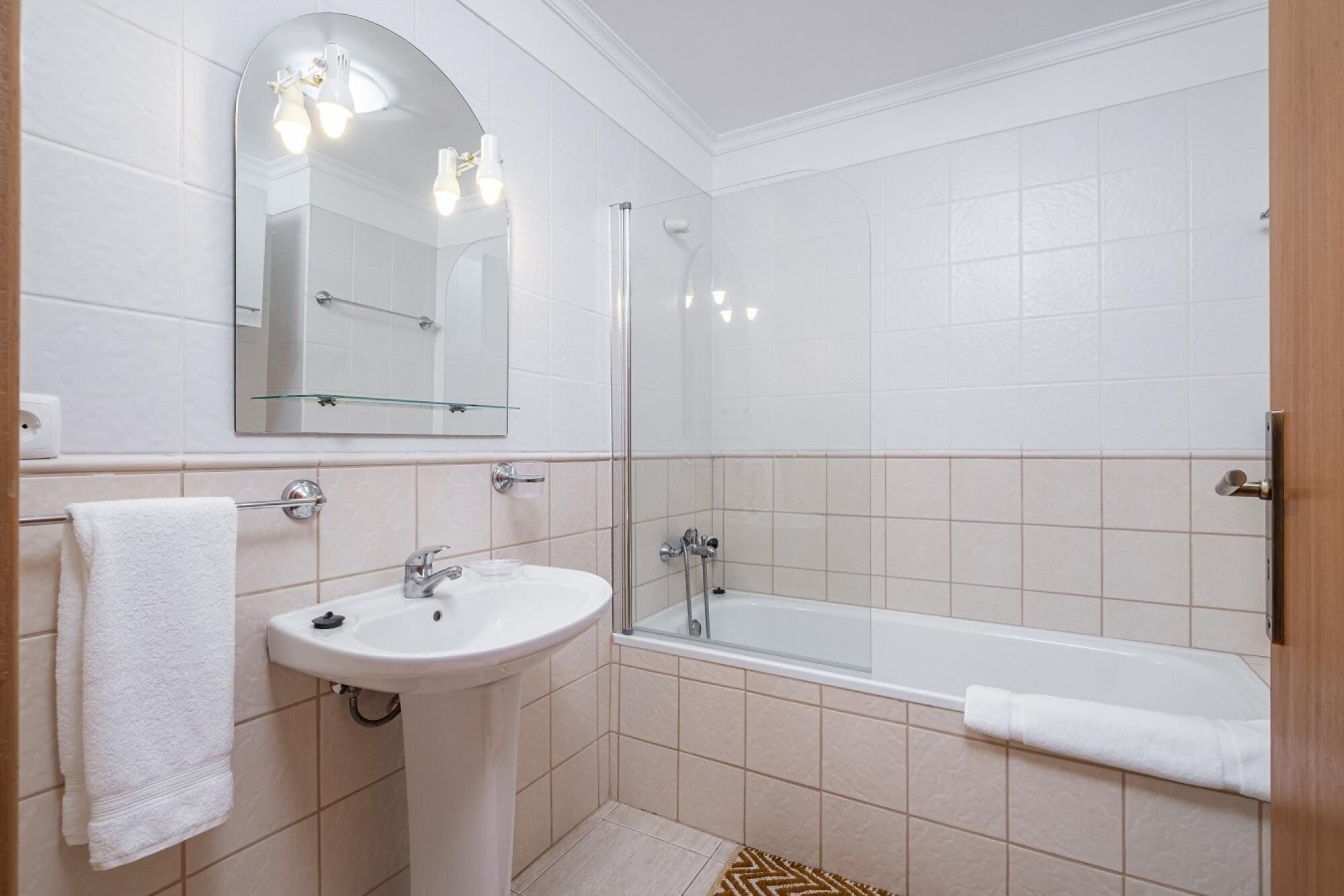 A bathroom with a sink, mirror, and shower.