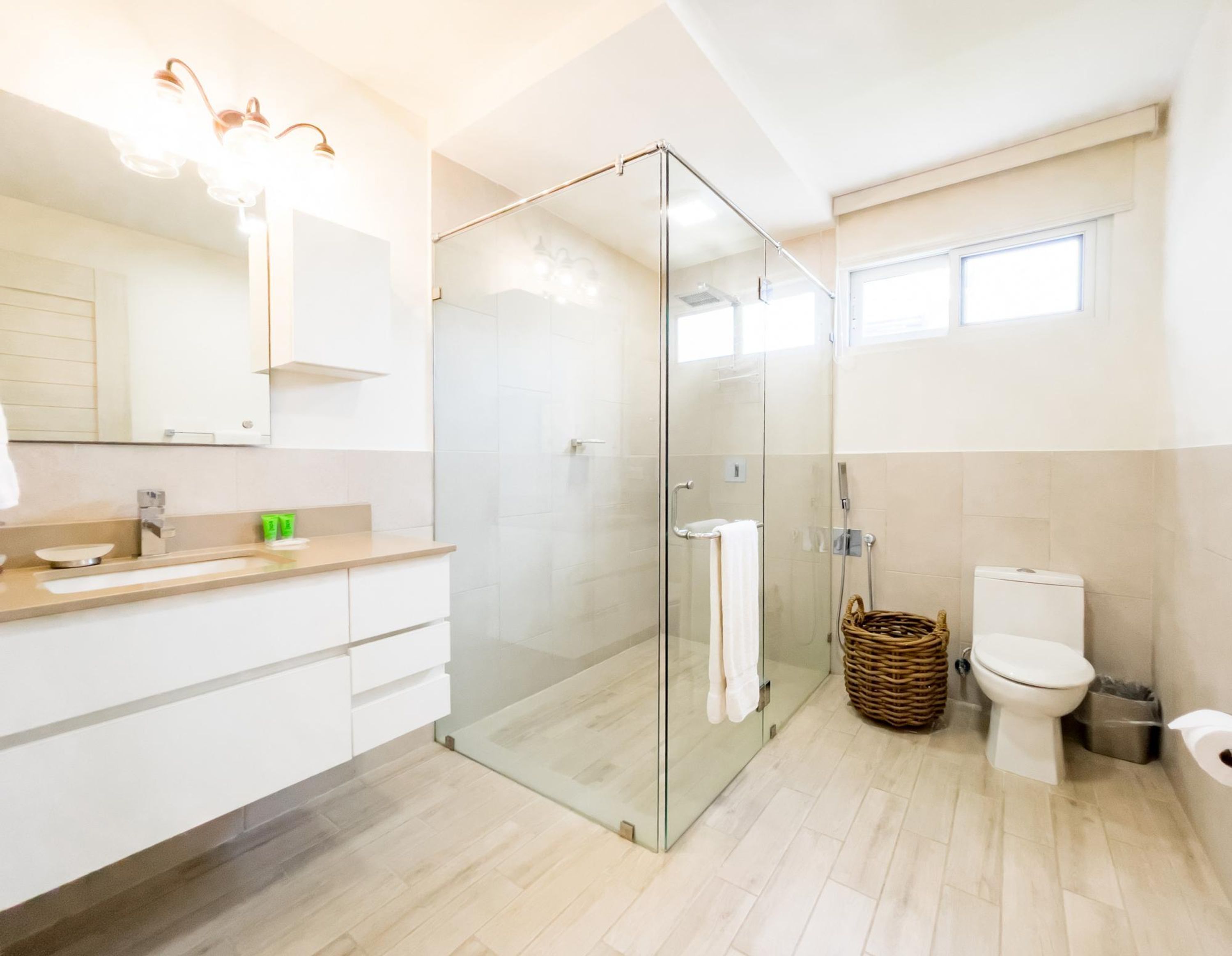 Un baño moderno con ducha de vidrio, inodoro y tocador con espejo y encimera.