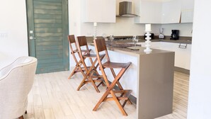 Une cuisine moderne dotée d’un îlot central, de chaises en bois et d’une cuisinière intégrée.