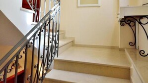 A staircase with a wrought iron railing, beige steps, and a wall-mounted mirror. - Katrina Superior Studio 4 With Balcony (Rethymno)