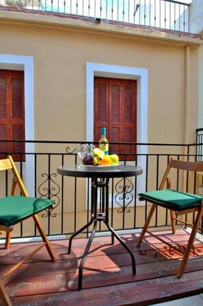 Ein Balkon mit rundem Tisch, zwei Stühlen und einer Obstschale.