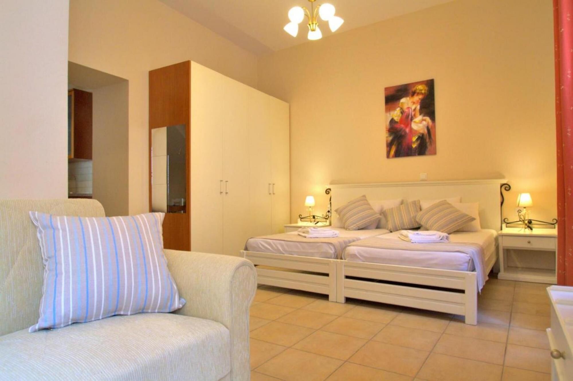 A bedroom with two beds, a sofa, a wardrobe, and a painting on the wall.