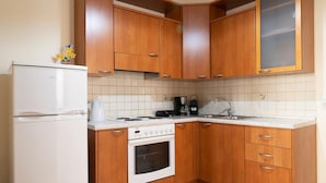 A kitchen with wooden cabinets, a white refrigerator, a stove, and a sink. - Katrina Superior Studio 4 With Balcony (Rethymno)