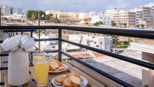 Ein Balkon mit einem Frühstückstisch, mit Blick auf die Stadt.