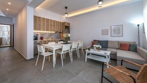 Ein modernes Wohnzimmer mit Essbereich, einer Couch und einer Küche im Hintergrund.