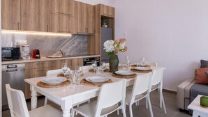Eine moderne Küche mit Holzausstattung, einem eingebauten Backofen und einem Essbereich für vier Personen, komplett mit weißen Stühlen und Geschirr mit Tellern und Gläsern.