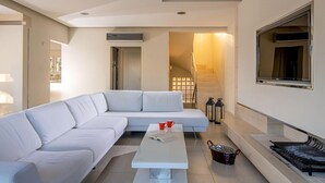 A modern living room with a white sectional sofa, a coffee table, and a staircase leading to an upper floor.