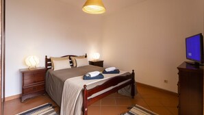 A bedroom with a bed, bedside lamps, a television, and a wooden nightstand. - A Torre by Acasadascasas (Mafra)