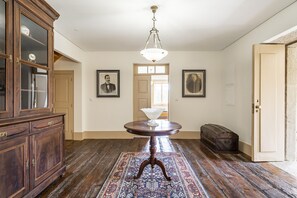 Ein geräumiger Raum mit Holzboden, einem runden Tisch mit einer Vase und einer Vitrine mit Glastüren.