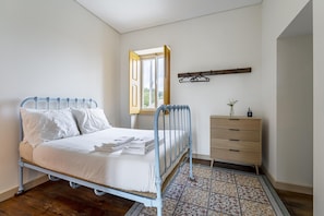 A bedroom with a metal bed frame, white bedding, a wooden dresser, and a patterned rug. - Nomad s Family - 4bdr Country House Macieira (Santa Maria da Feira)