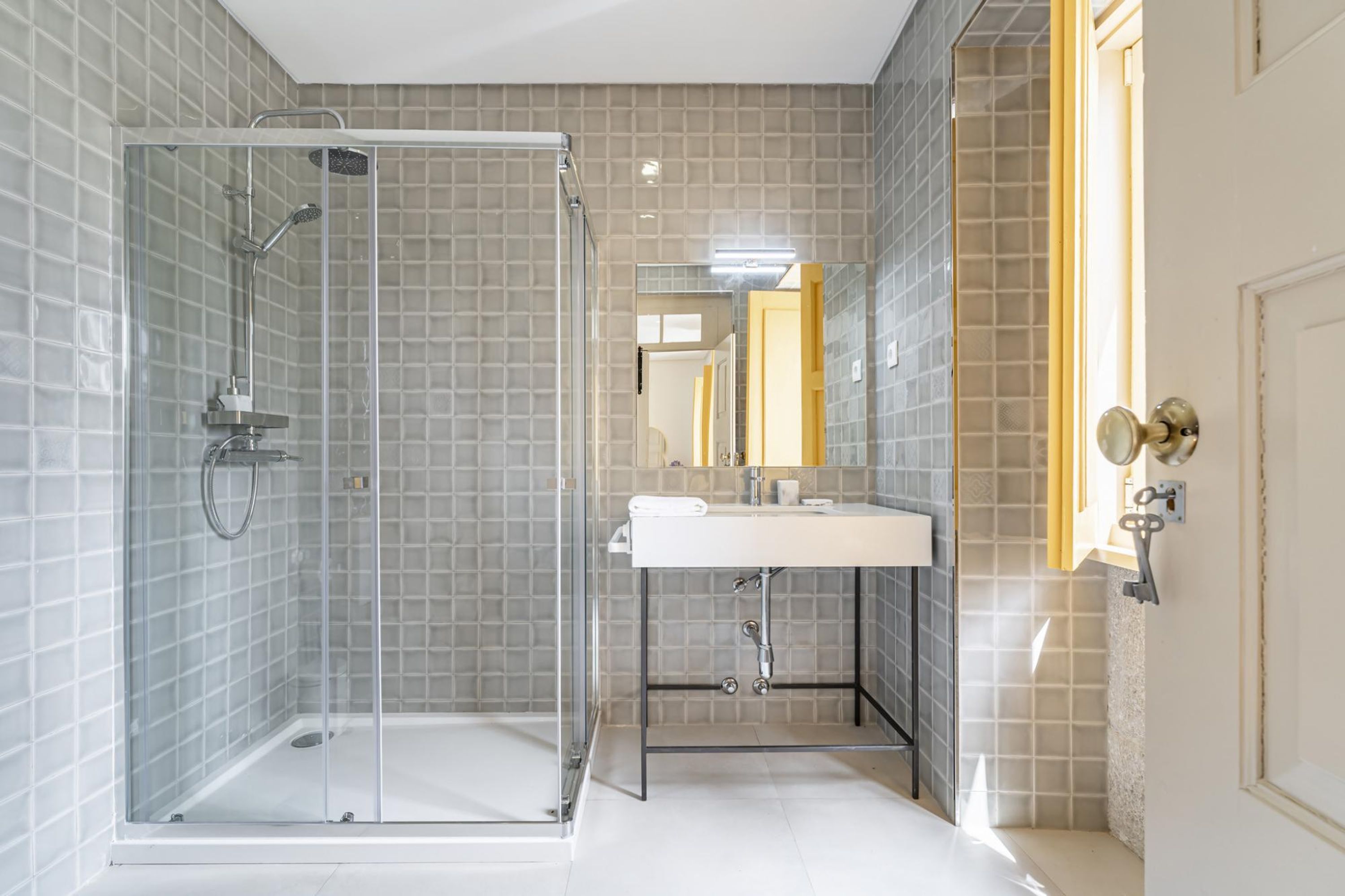 A modern bathroom with a glass-enclosed shower, a white sink, and a mirror above it.