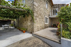 A stone building with a balcony, potted plants, and a concrete patio. - Nomad s Family - 4bdr Country House Macieira (Santa Maria da Feira)