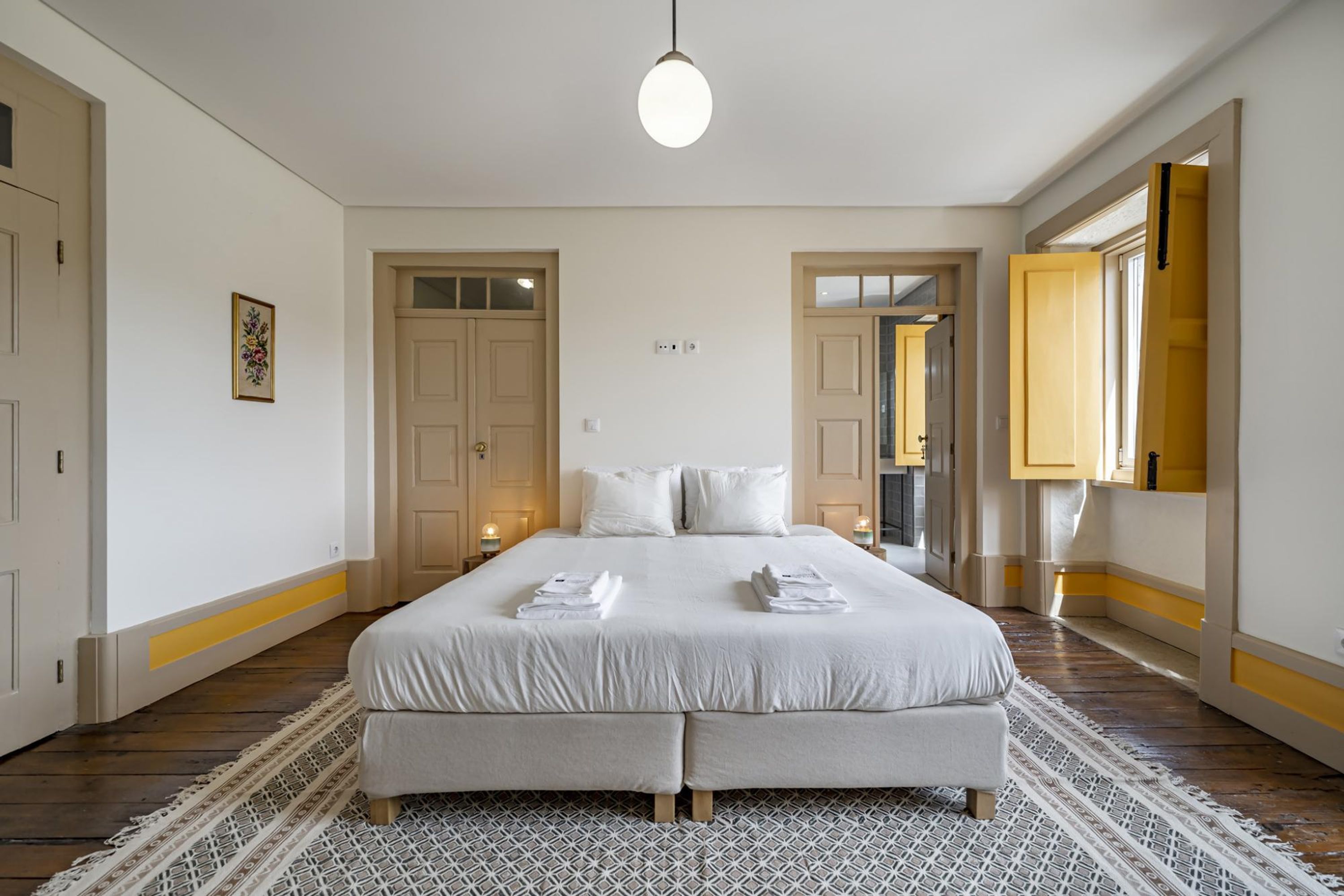 A spacious bedroom with a large bed, two bedside tables, and a hanging light fixture.