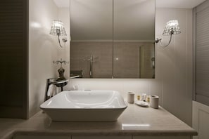 Un baño con un espejo grande, un lavabo blanco y dos luces empotradas.
