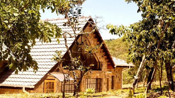 A rustic stone house with a sloped roof, a wooden door, and a small window.