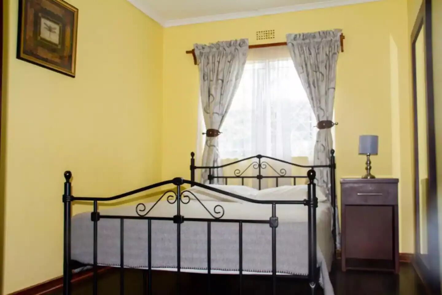 Une chambre avec un lit, une table de chevet et une fenêtre avec des rideaux.