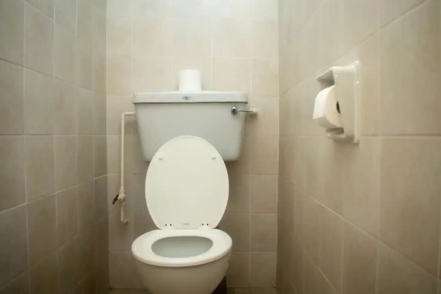 Ein kleines, sauberes Badezimmer mit Toilette, Toilettenpapierhalter und Wand-Bidet.