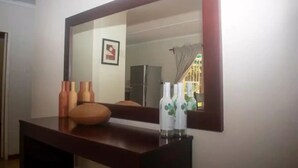 A room with a large mirror above a wooden dresser, a framed picture on the wall, and two bottles on the dresser. - Cosy 3 Bedroom Cottage - 2034 (Harare)