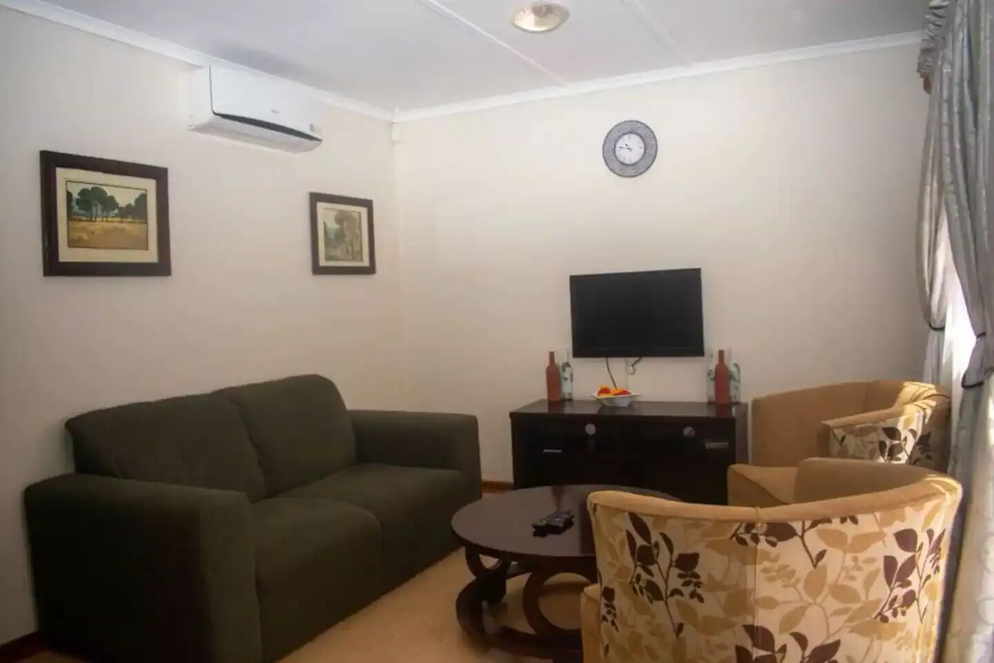 A living room with a sofa, a coffee table, a TV, and two chairs.