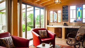 Une pièce chaleureuse avec un plafond en bois, de grandes fenêtres et un fauteuil rouge.