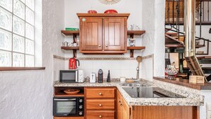 A kitchen with wooden cabinets, a microwave, a toaster, and a sink. - Ivy Cottage by Homie (Santana)