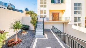 A modern building with a staircase leading to a balcony, surrounded by landscaped areas with various plants. - Gaula Residence by Homie (Santa Cruz)
