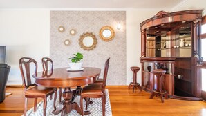 A dining area with a round wooden table, six chairs, a potted plant, and decorative wall mirrors. - Gaula Residence by Homie (Santa Cruz)