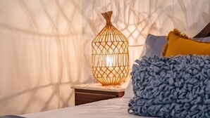 A bedroom with a bed, a nightstand, a decorative lamp, and a patterned wallpaper. - Gaula Residence by Homie (Santa Cruz)