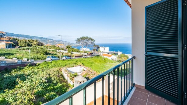 A balcony with a view of a coastal town, including houses and a tree. - Gaula Residence by Homie (Santa Cruz)