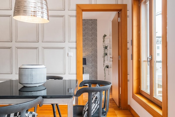 Enjoy meals in this dining area with a table and chairs, a stylish lamp, and a window offering a view of the outdoors.