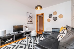 Relax in this stylish living room with a black leather sofa, flat-screen TV, and glass coffee table.