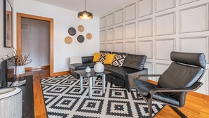 Un salon moderne avec un canapé, un fauteuil, une table basse et des assiettes décoratives accrochées au mur.