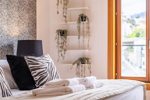 Experience a calm and inviting space with a neatly made bed, city views, and a touch of personal style.