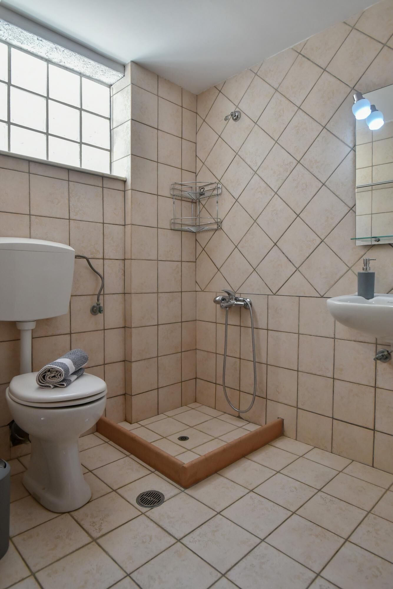 Et badeværelse med brusebad, toilet og håndvask.