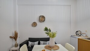 A modern dining area with a white table, chairs, and a decorative vase with green plants. - Apartments for 3 1st Floor (Malevizi)