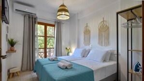 A hotel room with a bed, a hanging light fixture, a plant, and a view of the outdoors. - Apartments for 3 1st Floor (Malevizi)