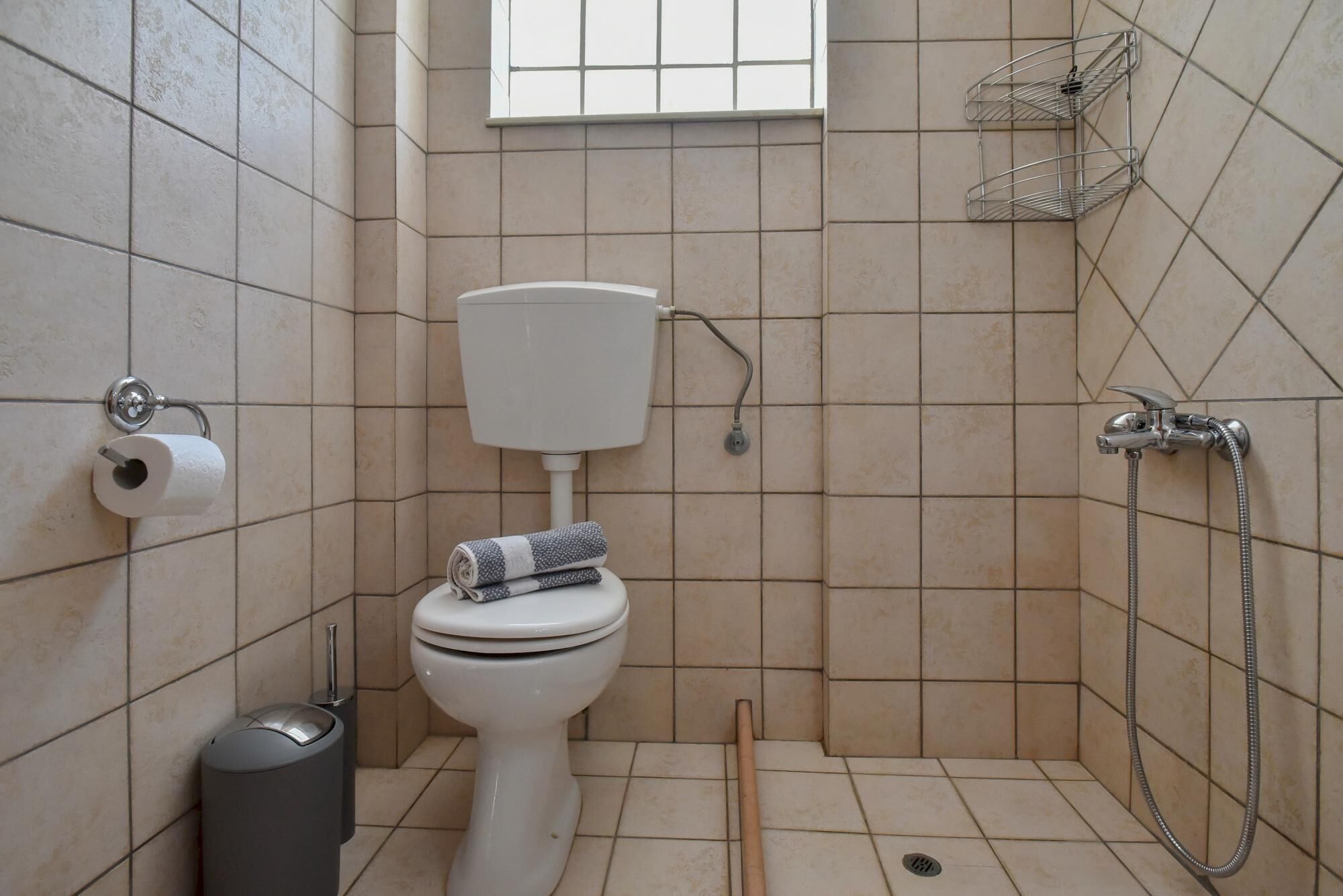 A small bathroom with a toilet, a shower, and a window.