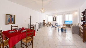 Un coin repas avec une nappe rouge, des chaises en bois et un tableau accroché au mur.