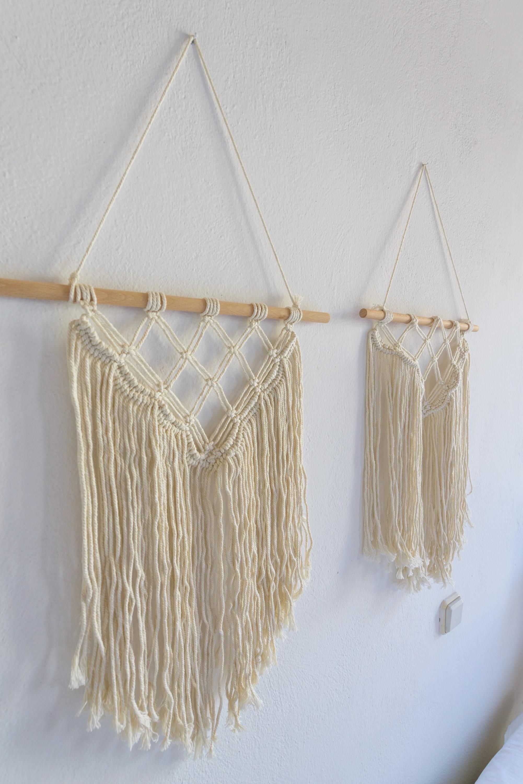 Two macramé wall hangings suspended from a wooden rod.