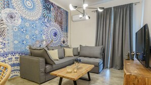 A modern living room with a grey sofa, a wooden coffee table, and a patterned wall.