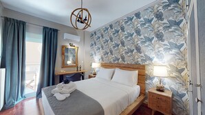 A hotel room with a bed, a desk, a chair, a mirror, and a window with curtains.