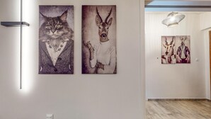 A hallway with three framed artworks on the wall, a modern light fixture, and a wooden floor.