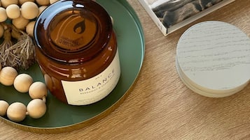 A candle and a small potted plant sit on a table, accompanied by a book with a coastal theme.