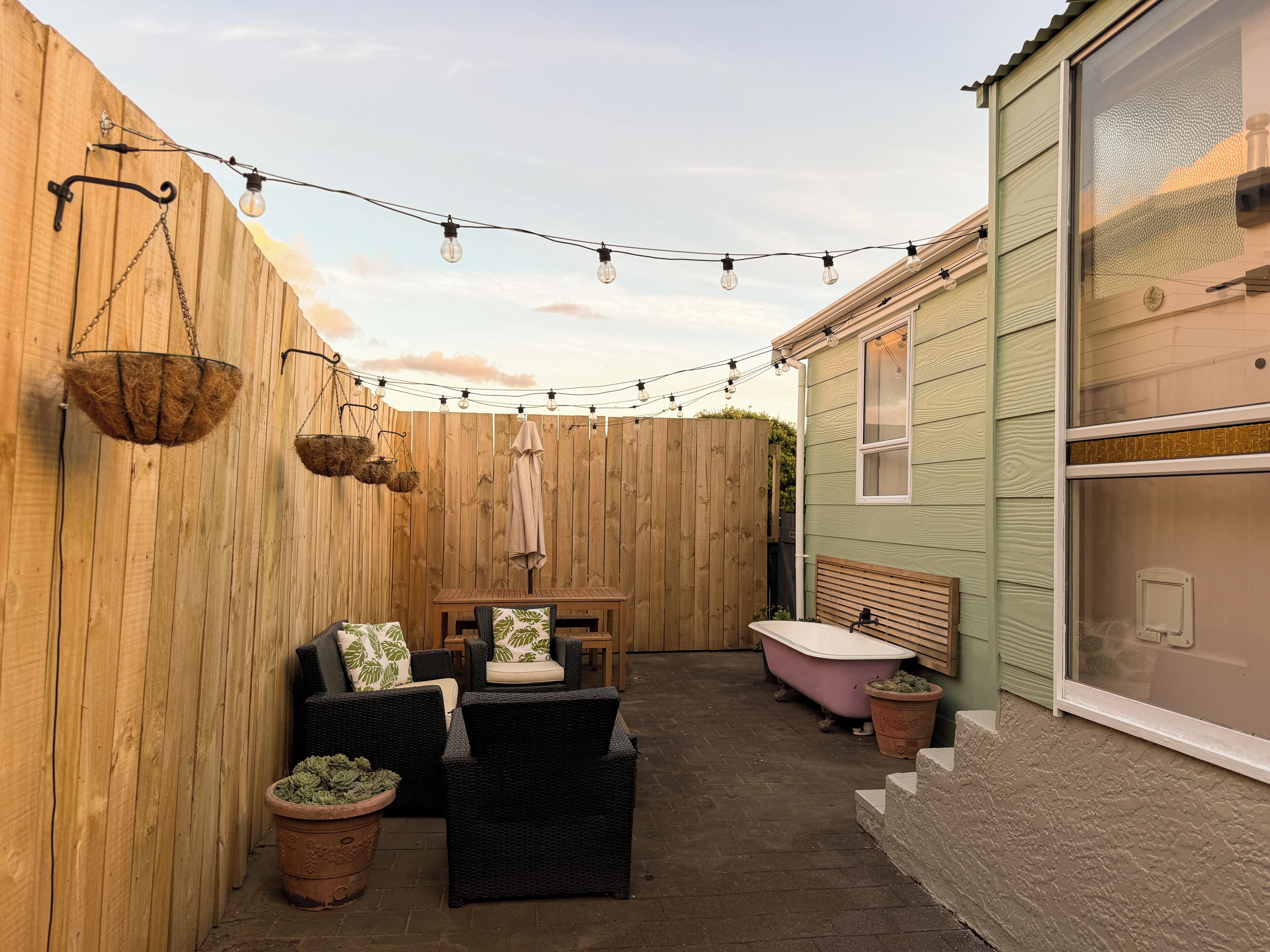 Cozy private patio with string lights, lounge seating, and outdoor tub