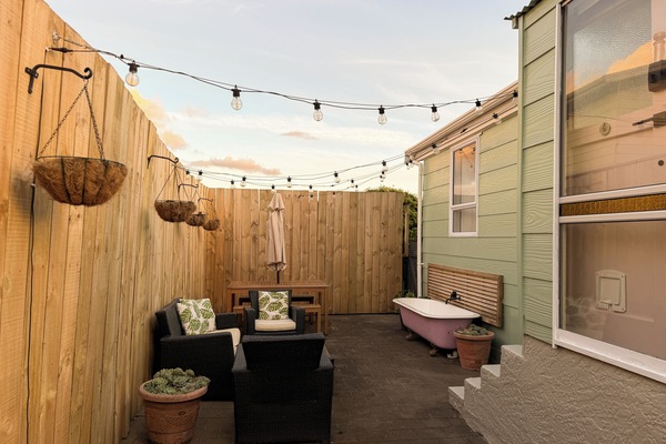 Cozy private patio with string lights, lounge seating, and outdoor tub
