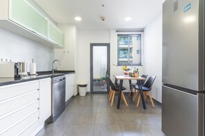 A modern kitchen with a dishwasher, a dining table with chairs, and a refrigerator. - Funchal Frui Vita by Atlantic Holiday (Funchal)